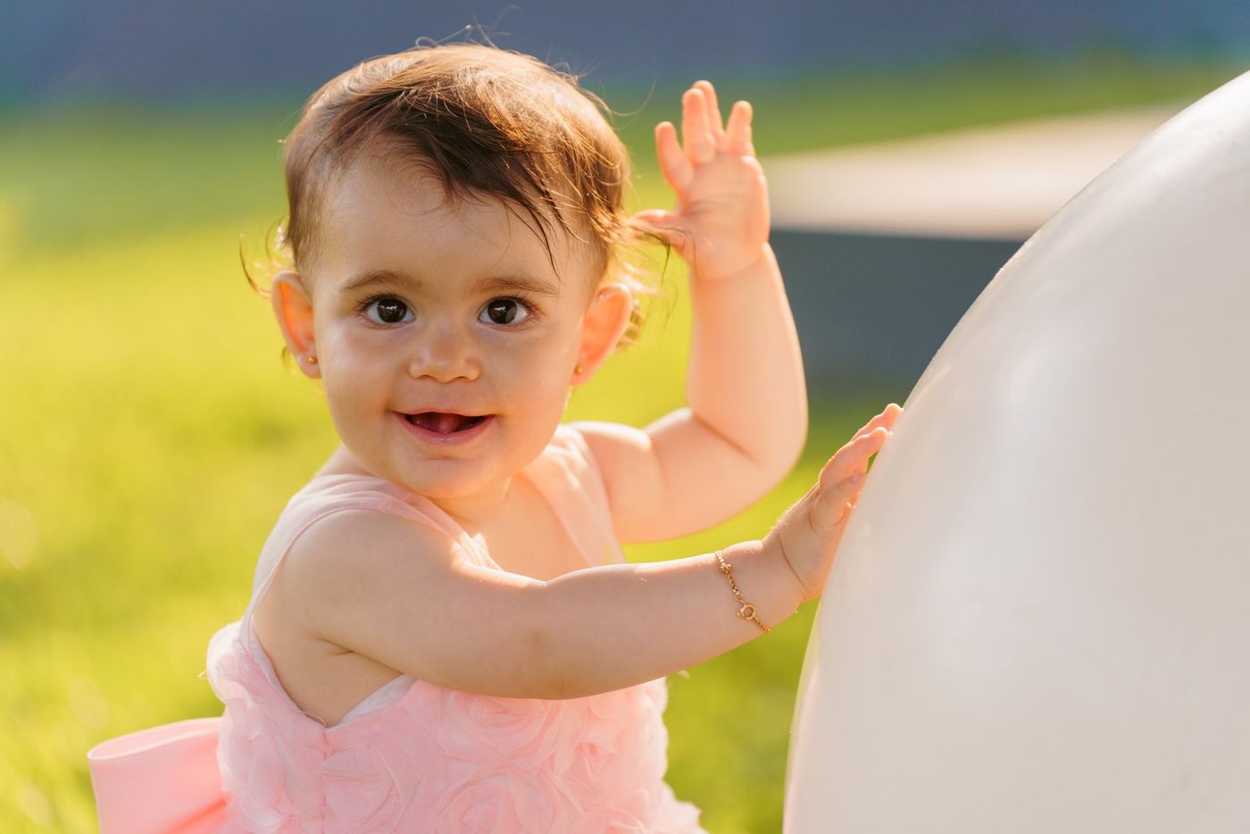 Baby waving next to a balloon