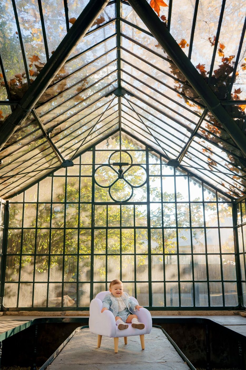 Baby in an armchair inside a glasshouse