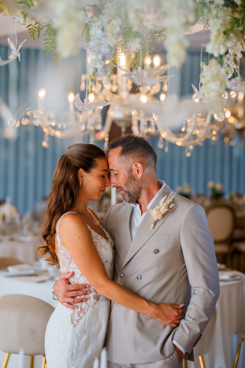 Bride and groom forehead to forehead in a bright hall