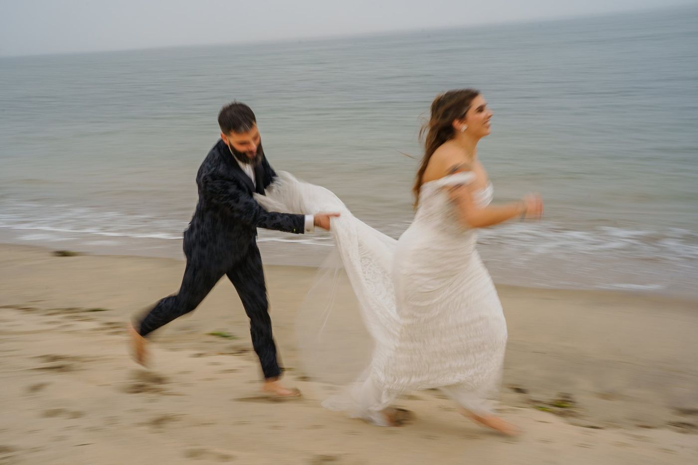 Bride and groom running on the beach