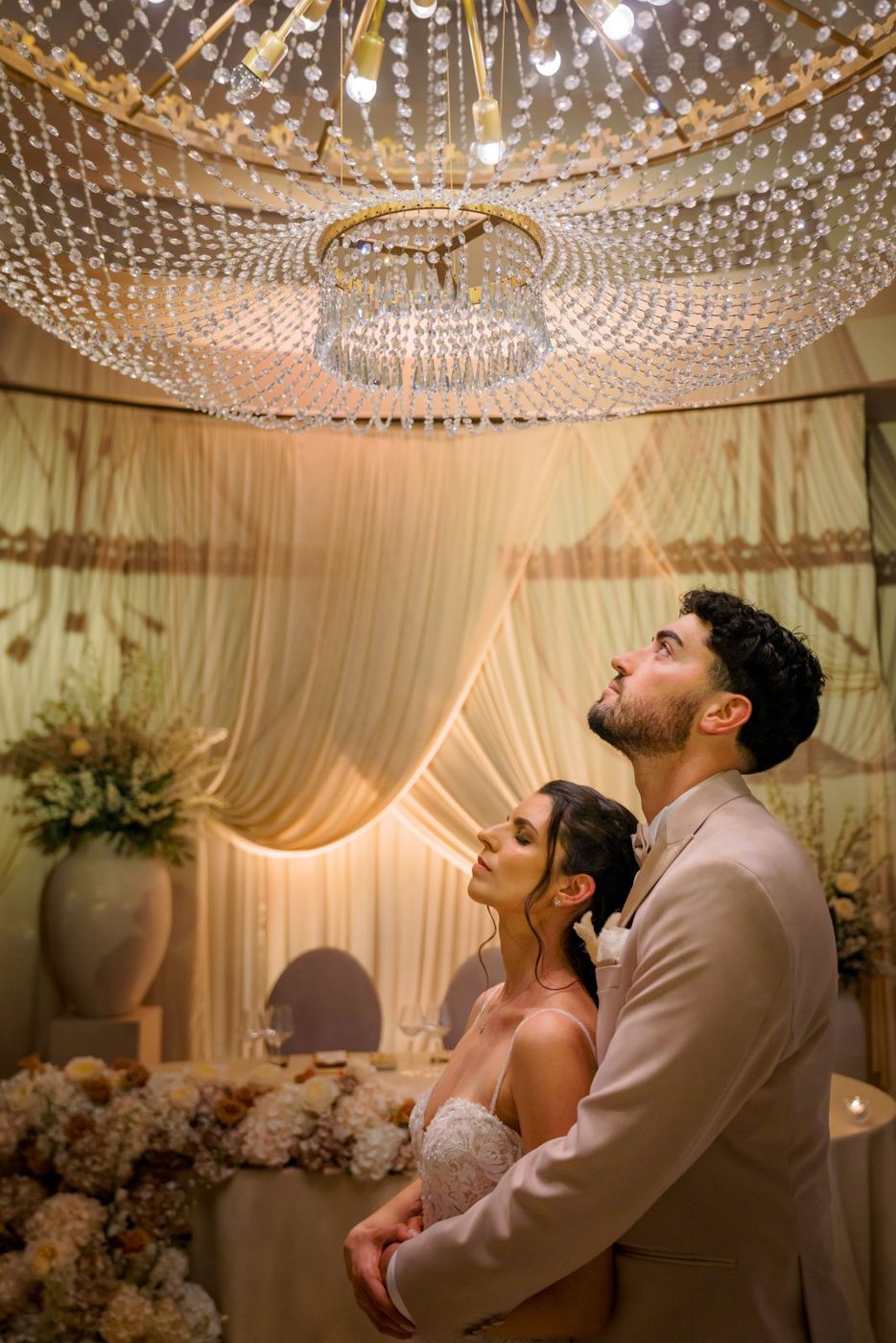 Bride and groom looking up at a crystal chandelier
