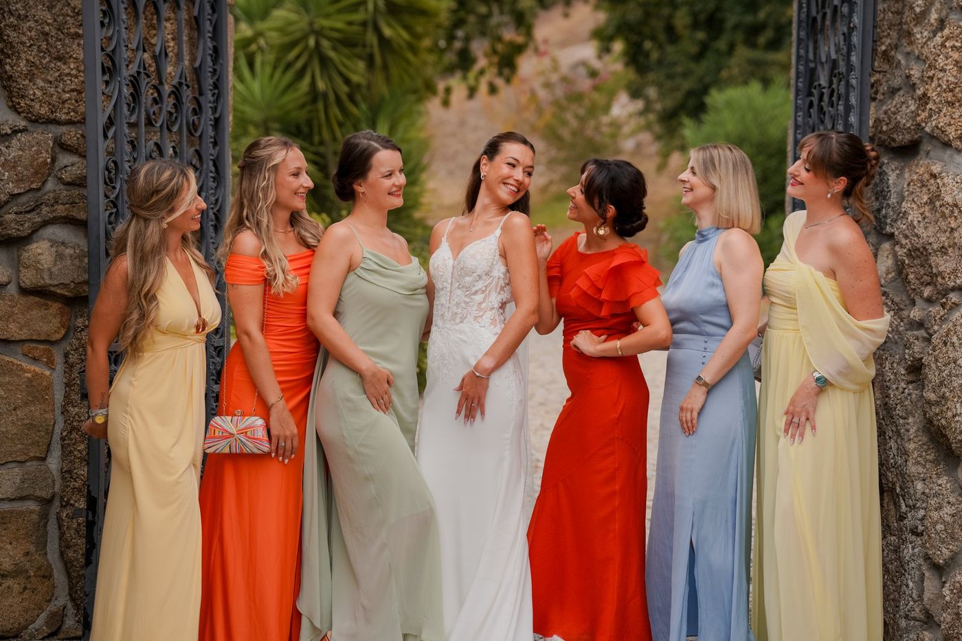 Bride with her bridesmaids by a stone gate