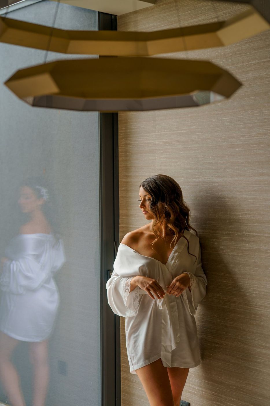 Bride in her robe, reflected in the glass