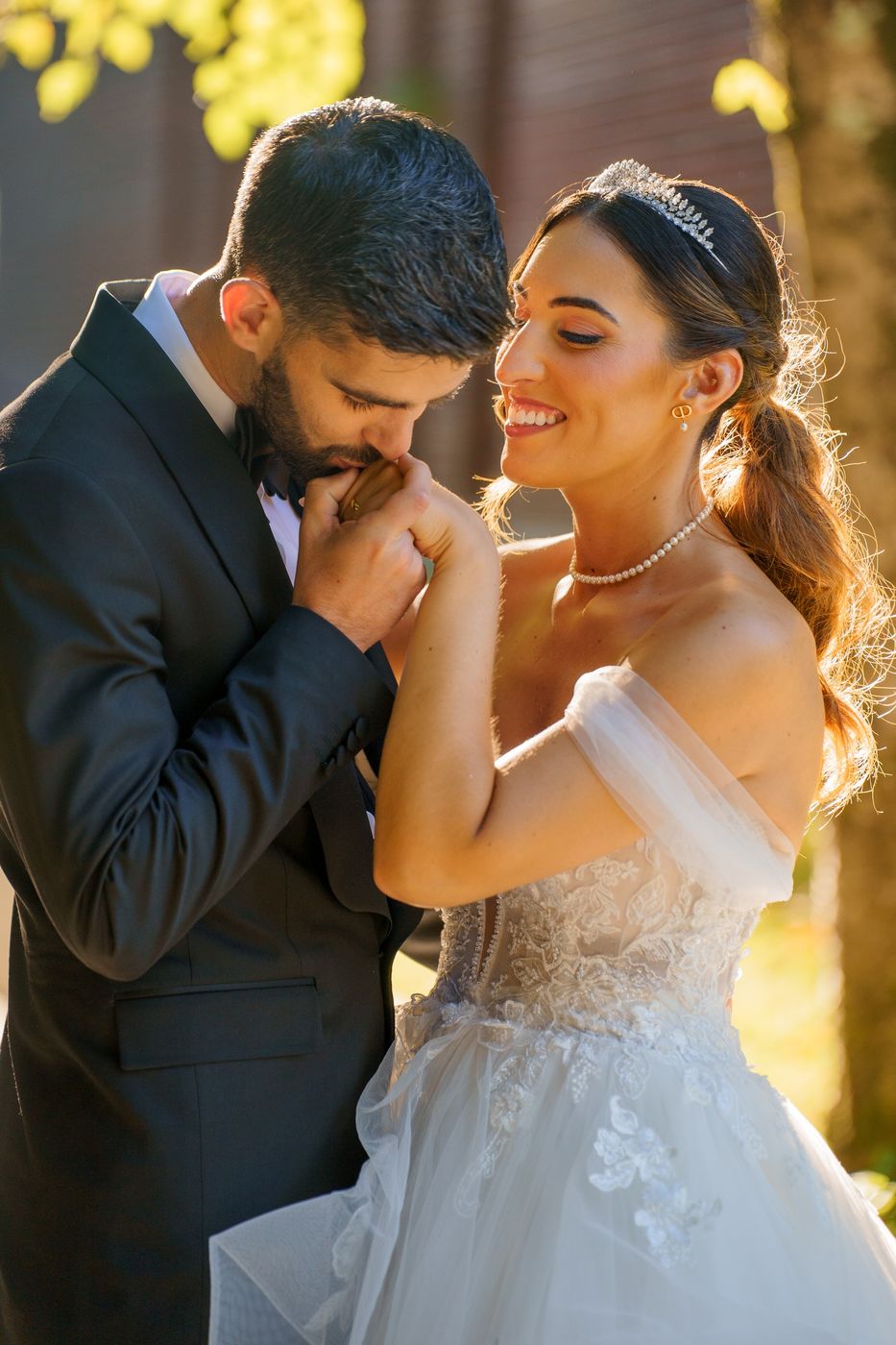 Groom kissing the bride's hand, backlit