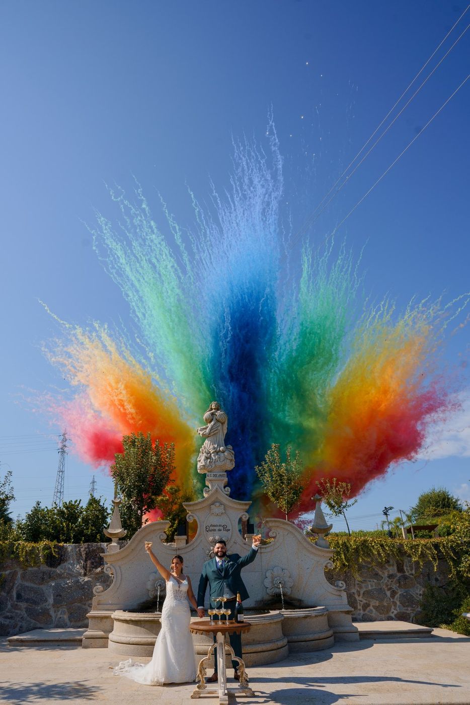 Bride and groom with arms raised in coloured smoke