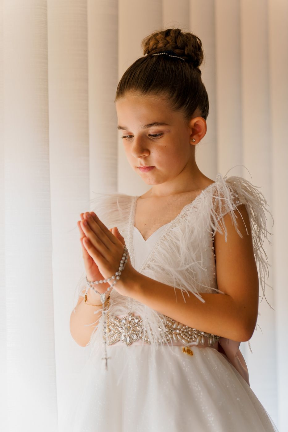 Girl praying with her rosary by the window