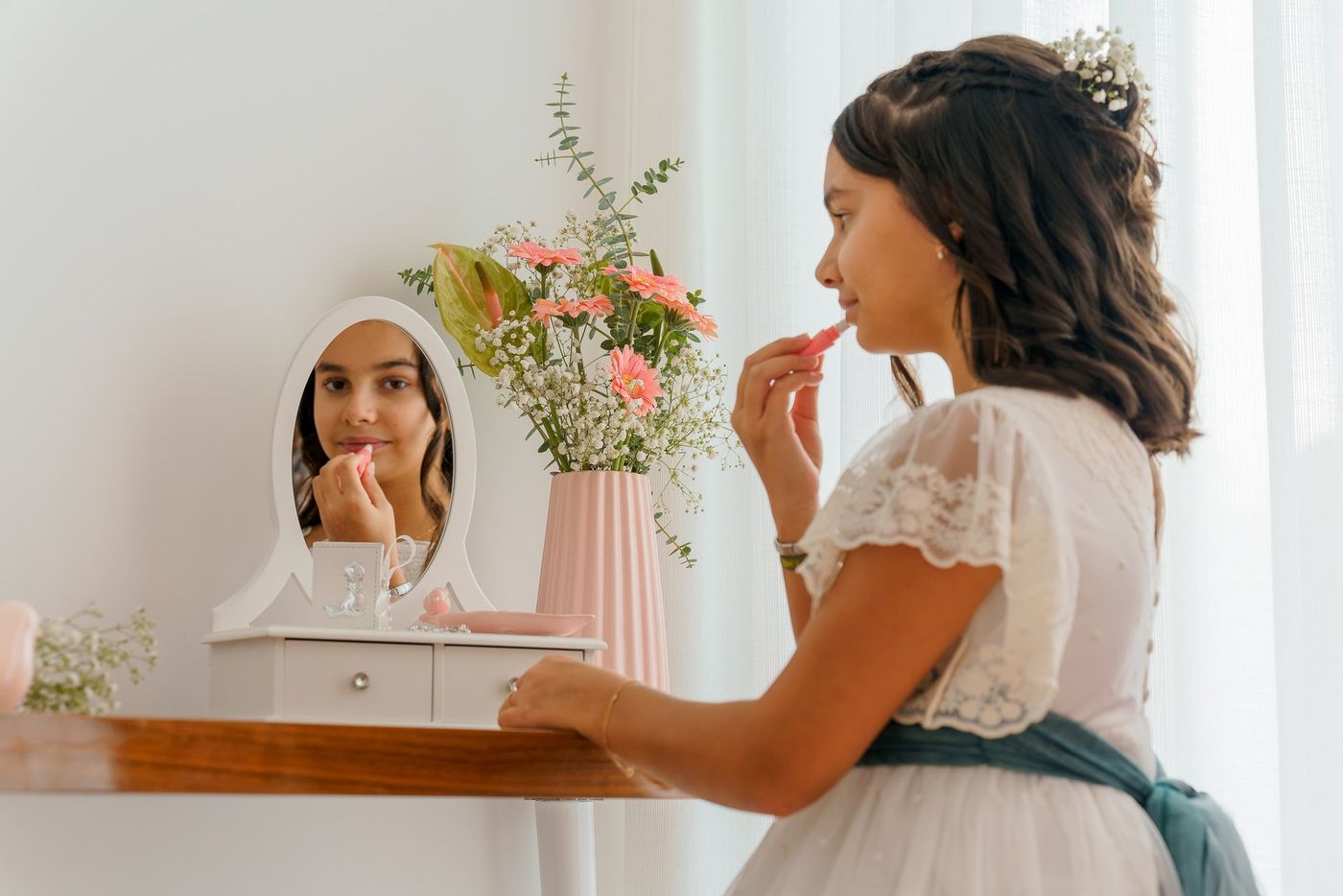 Girl putting on lipstick in the mirror