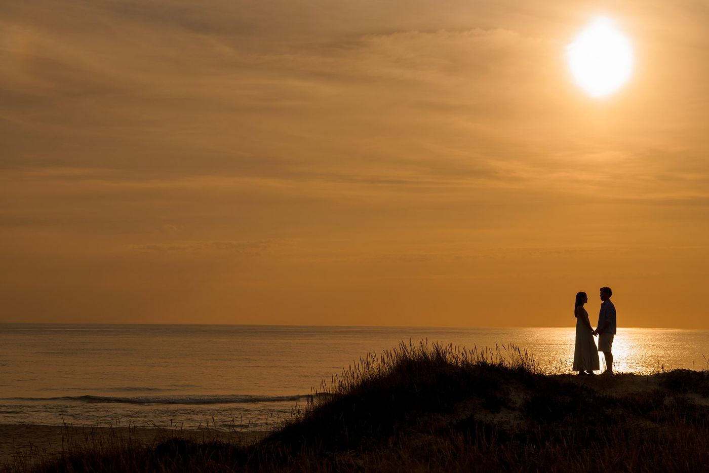 Couple silhouetted on top of the dunes