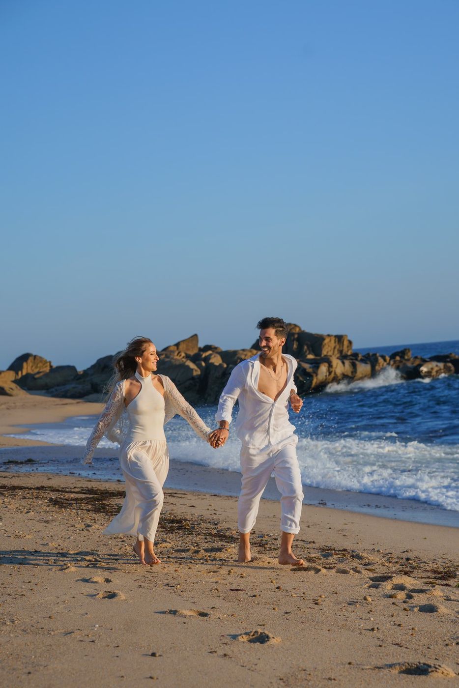 Couple walking on the beach by the rocks