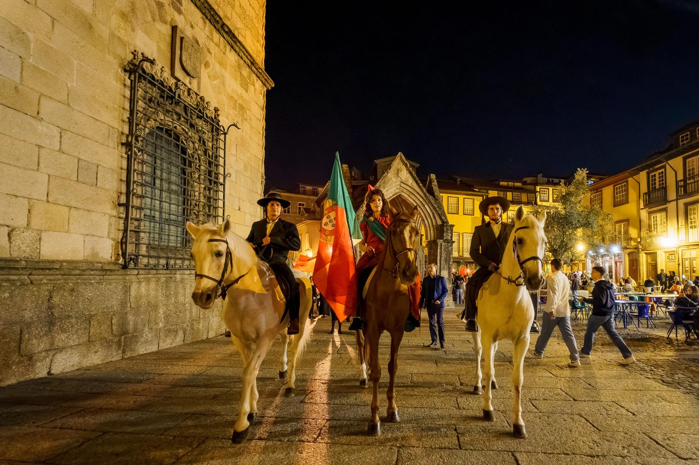 Desfile a cavalo numa praça histórica, à noite