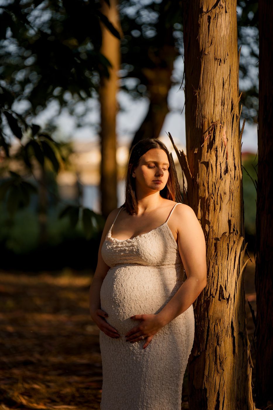 Mum-to-be leaning against a tree at the end of the day