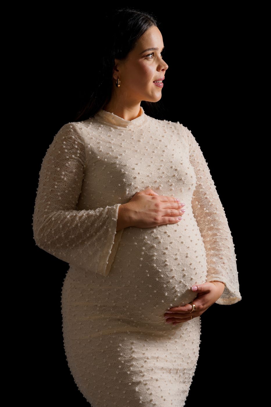 Mum-to-be in a light dress, in the studio on a black background