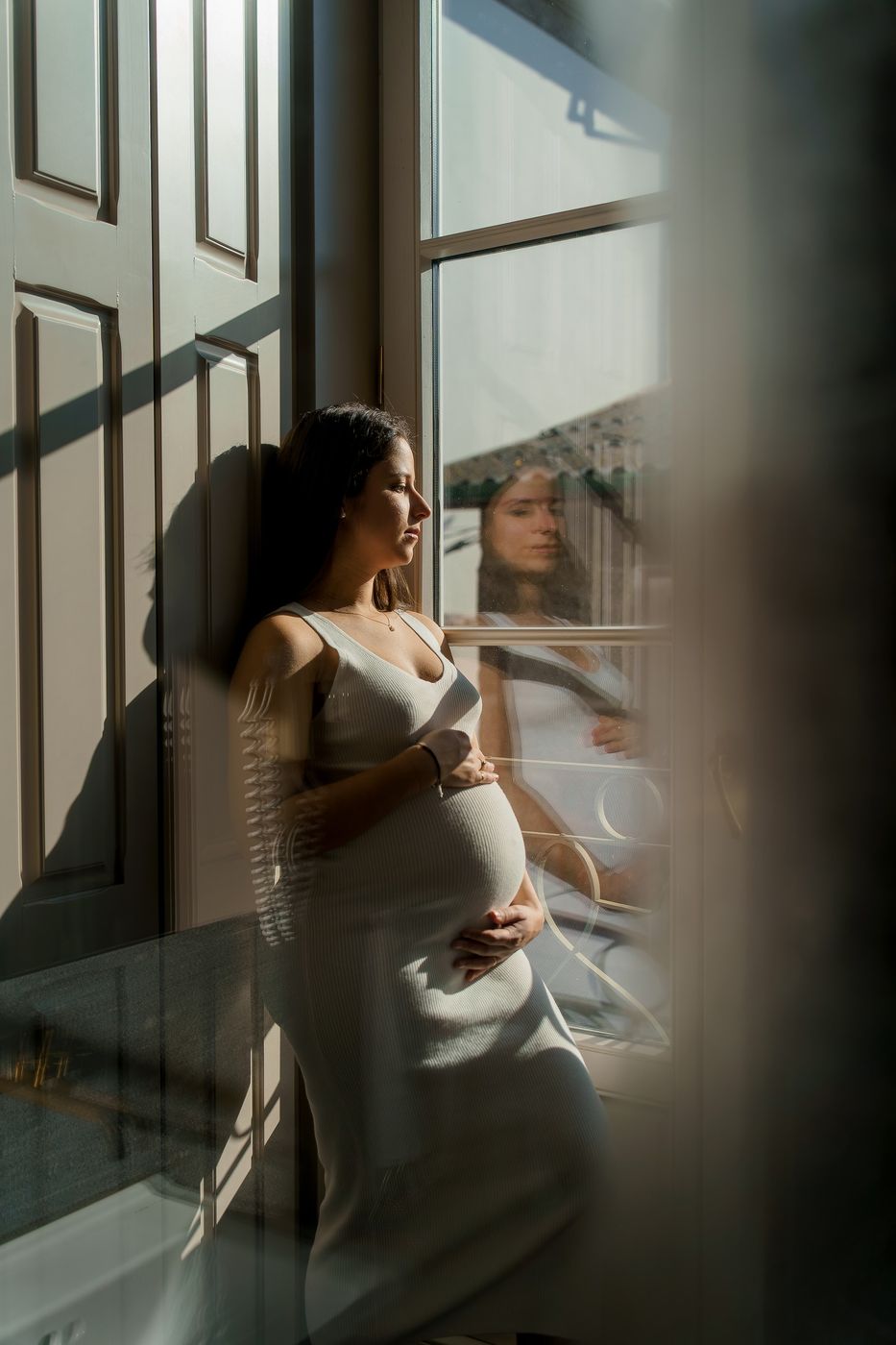 Mum-to-be at the window, reflected in the glass