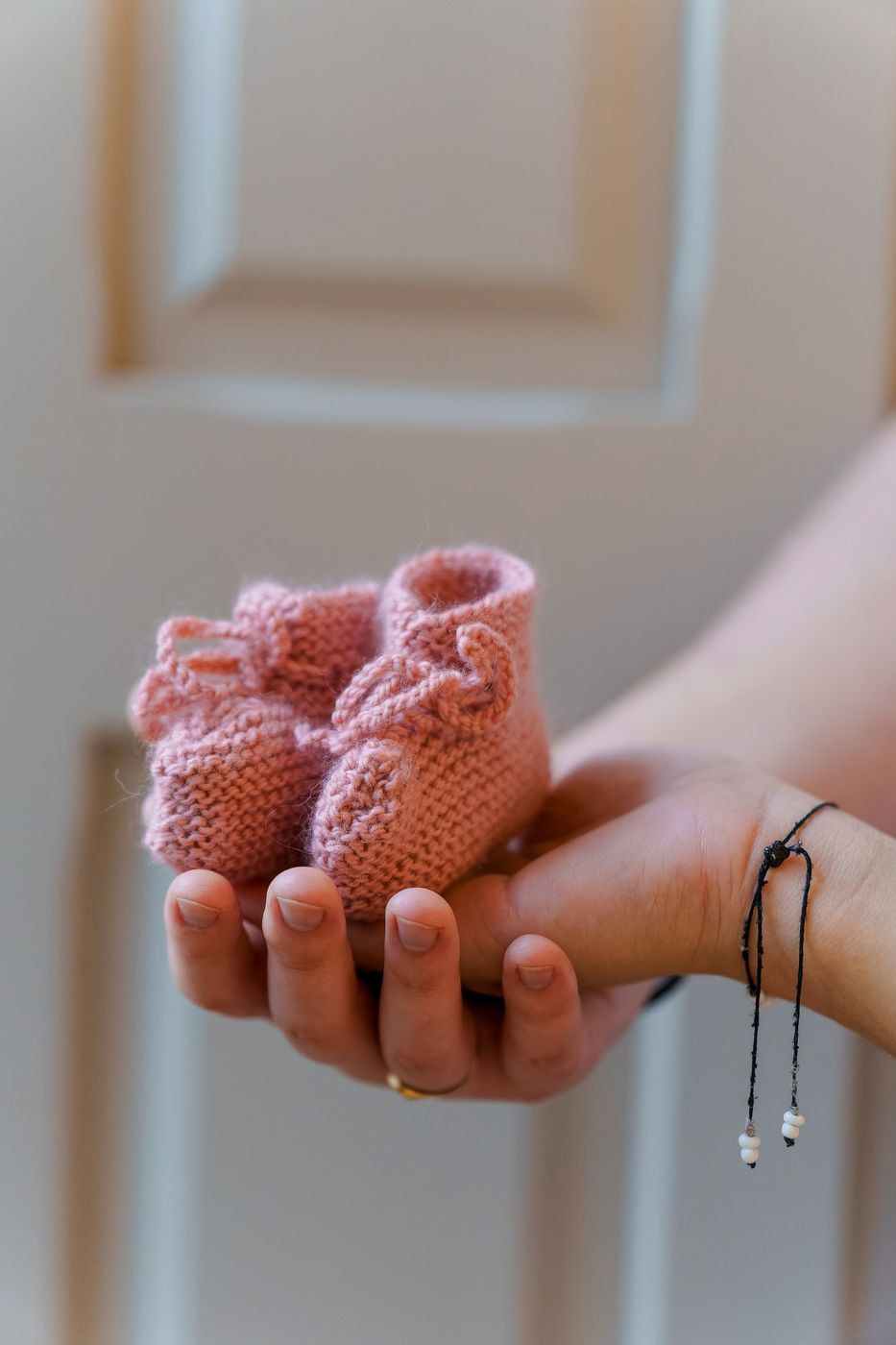 Pink knitted baby shoes in mum's hand