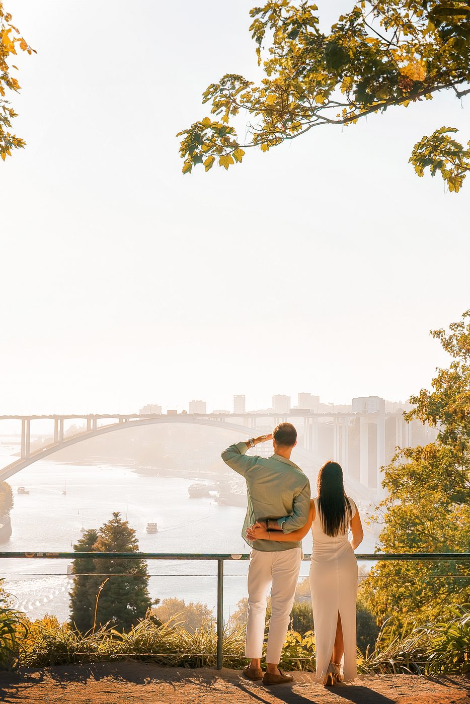 Casal a olhar a ponte sobre o Douro, entre árvores