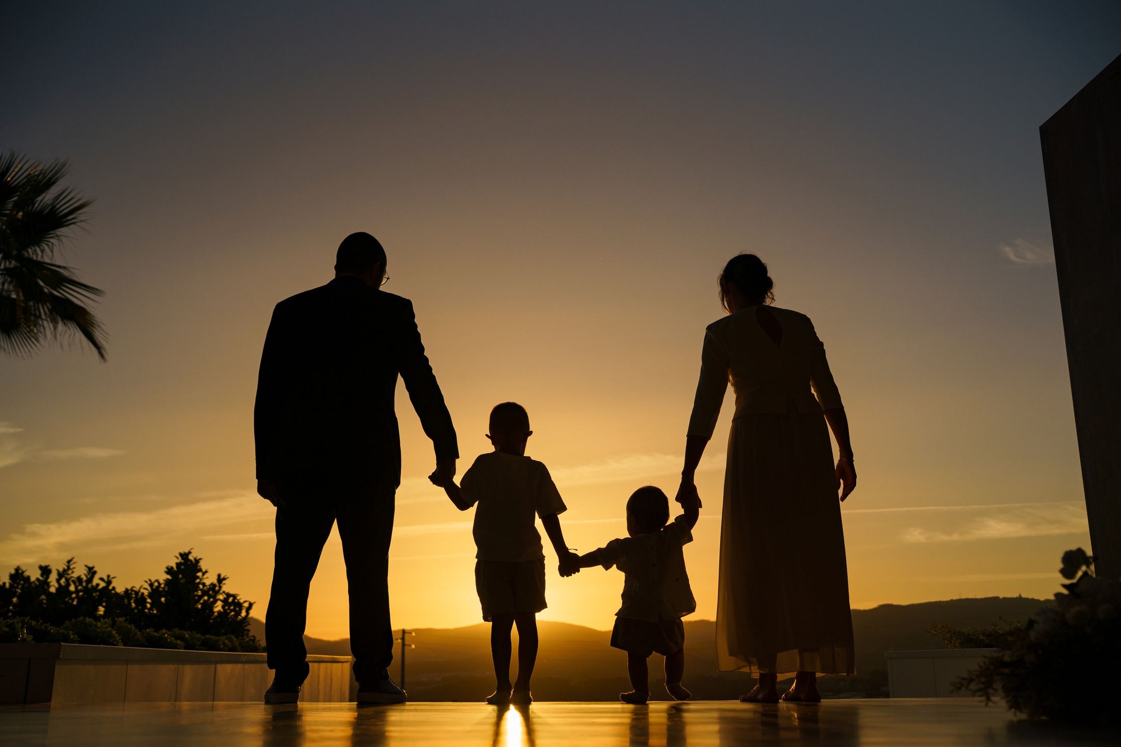Family silhouetted at sunset, holding hands with two children